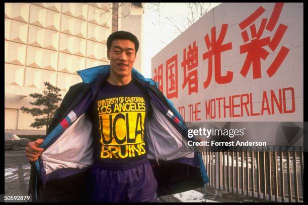 Chinese basketball star Ma Jian sporting UCLA Bruins t-shirt, re winning scholarship to Amer. Univ., outside, by do credit to Motherland banner.