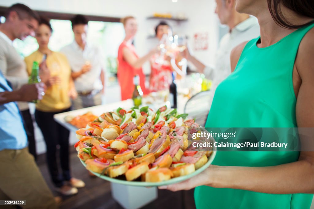 Frau serviert Tablett mit Essen auf party