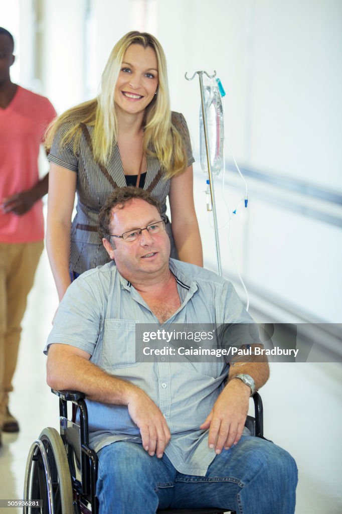 Woman wheeling father in hospital hallway