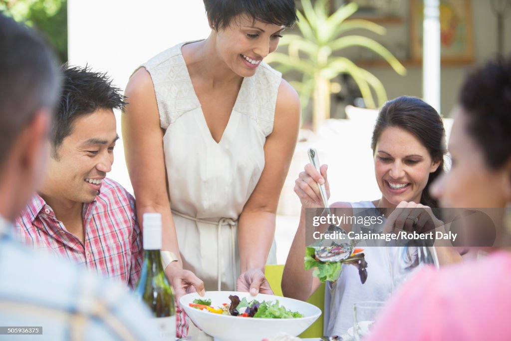 Femme servant des amis à table à l’extérieur