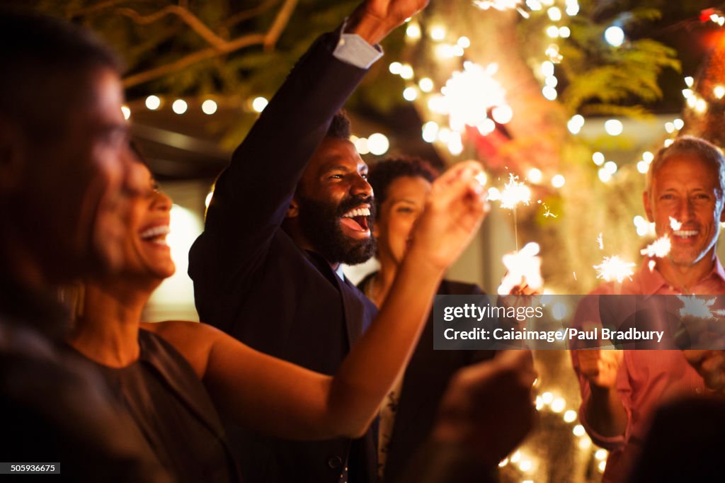 Friends playing with sparklers at party