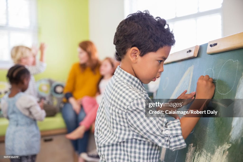 Student drawing on chalkboard in classroom