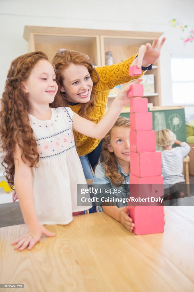 Students and teacher stacking blocks in classroom