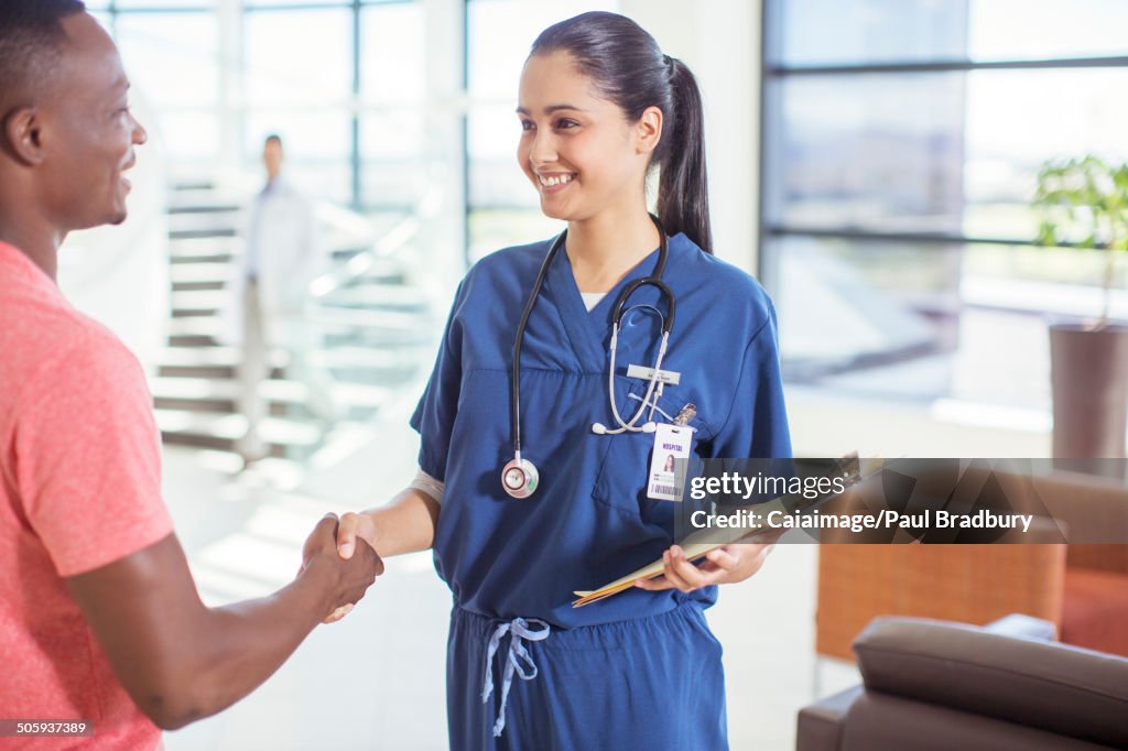 Nurse and patient shaking hands in hospital