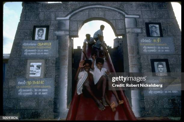 Boys on playground sliding pond w. Arch birth/death-dated pics of secessionist Tamil Tiger LTTE cadre battle-dead; Point Pedro, Jaffna pensinsula.