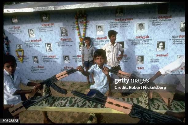 Boys on war-theme seesaws w. Bkgrd. Birth/death-dated pics of secessionist Tamil Tiger LTTE cadre battle-dead; Point Pedro, Jaffna peninsula, Sri...