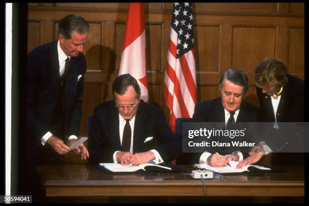 Pres. Mulroney & Pres. Bush sitting, framed by flags, penning acid rain agreement in signing ceremony at Parliament bldg. In Ottawa, Canada.