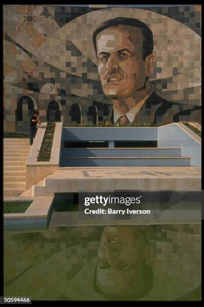 Mosaic wall mural imaging Pres. Assad reflecting in pool below.