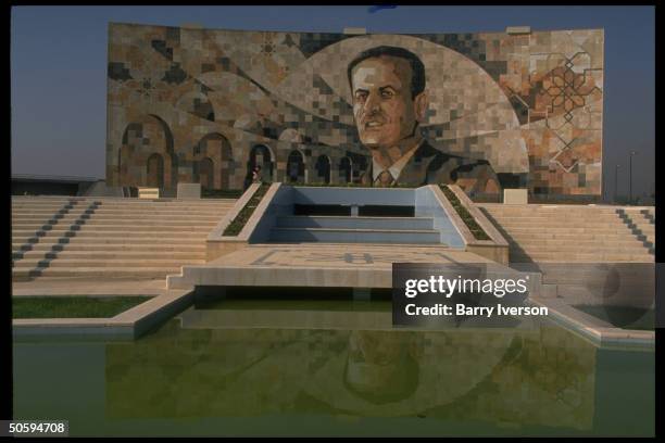 Mosaic wall mural, featuring larger-than-life portrait of Pres. Assad, reflecting in pool below.