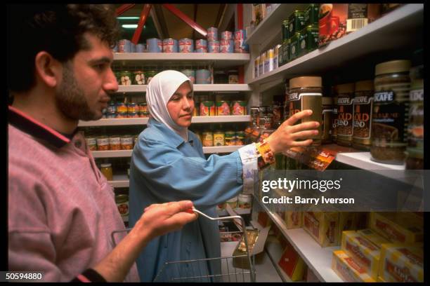 Shopper reaching for jar of Nescafe instant coffee above shelf lined w. Boxes of Lipton tea, at supermarket stocking previously banned imports.