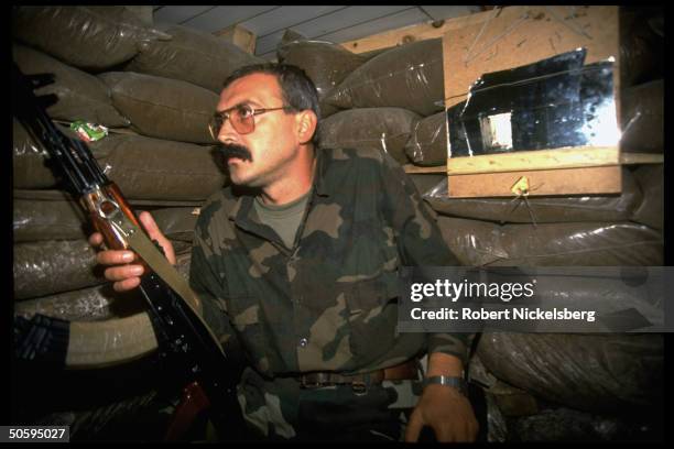 Croat soldier of HVO force in sandbagged bunker, w. Rifle, on civil war front along western bank of Neretua River in former Yugoslav republic.