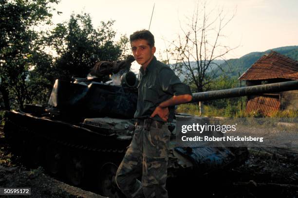 Bosnian Serb soldier by Russian T-55 tank, graffiti-covered, on Muslim-surrounded, Serbian-held civil war front in ex-Yugoslav republic.