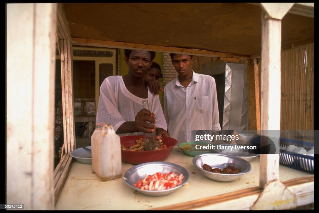 Street food vendor mashing mixture w. em