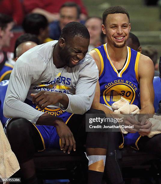 Draymond Green and Stephen Curry of the Golden State Warriors share a laugh on the bench near the end of a game against the Chicago Bulls at the...