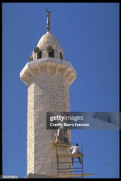 Scaffold perchers sprucing up mosque minaret at Palestinian Baqaa refugee camp, world's largest, housing 1948 & 1967 Arab/Israeli war refugees.