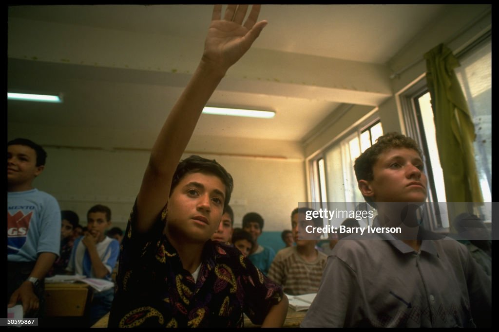 Palestinian students, 1 raising hand, in