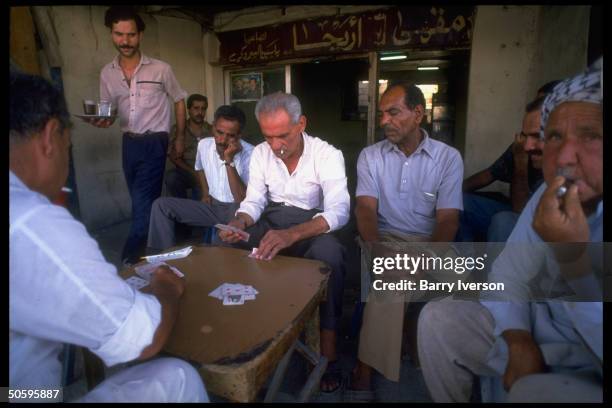 Waiter glancing at card-playing men at Jericho coffee shop at Palestinian Baqaa refugee camp, world's largest for refugees fr. 1948 & 1967.