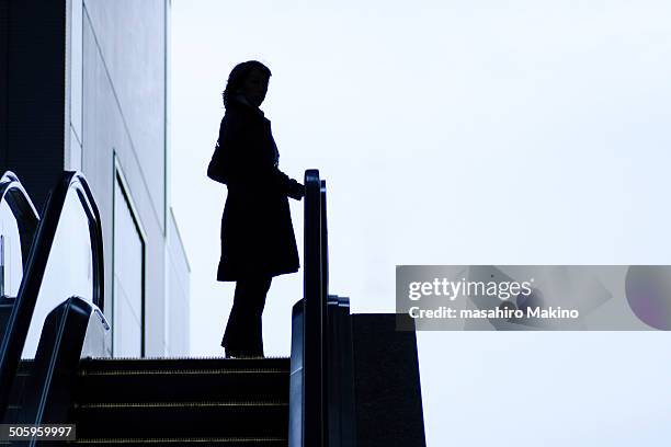 silhouette of woman on escalator - escalator side view stock pictures, royalty-free photos & images