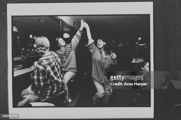 Hofstra Univ. Student Karen Ellick , looking on as Shana Westhoff high-fives fellow student Kathryn Littlefield while romping & drinking in bar; they...