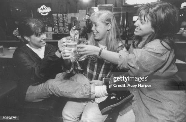 Hofstra Univ. Students Rachel Shanken, Jan Eresthena & Shana Westhoff raising beer glasses in toast while sitting in bar; they are members of Douglas...