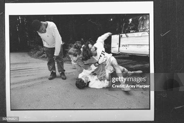 Hofstra Univ. Student Gemps Michelot looking on as School adminstrator Tamra Cimalore & Rennie Gross pin Craig Gordon to the ground nr. Their school...