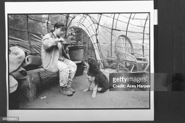 Hofstra Univ. Student Shana Westhoff enjoying meal while sitting on bench, as the camp dog watches her at the Green Tortoise People compound; Shana...