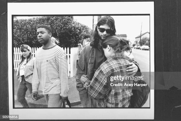Hofstra Univ. Student Jay Caputo hugging Rennie Gross while Gemps Michelot & unident. Female student walk by nr. Street corner; they are part of prof...