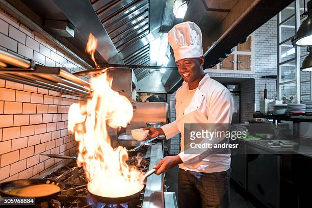 chef flaming food at a restaurant - black cook stockfoto's en -beelden