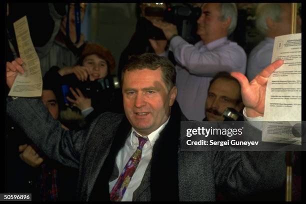 Ultra-nationalist Liberal Democrats ldr. Vladimir Zhirinovsky waving ballots, framed by photographers, voting in parliamentary elections.