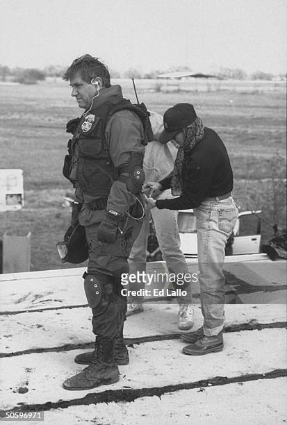 Actor Dan Lauria in combat garb as an ATF cmdr., getting his belt equipment checked by female wardrobe asst. During break in filming of TV movie In...