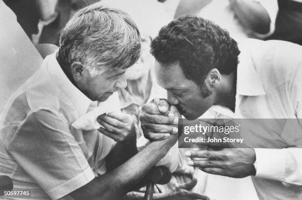 Ldr. Cesar Chavez at mass, getting his hand kissed by black ldr. Rev. Jesse Jackson who is passing a cross to him as he joins Chavez's fast on behalf...