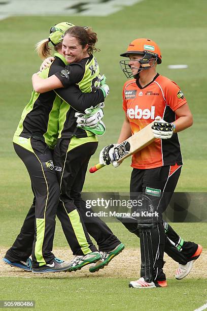 Thunder players celebrate after winning the Women's Big Bash League match as Nicky Shaw of the Perth Scorchers reacts between the Sydney Thunder and...