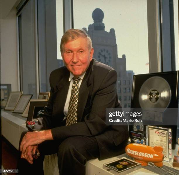 Viacom Inc. Chmn. Sumner Redstone in office w. Paraphernalia fr. Various co. Divisions, incl. Plastic blimp bearing Nickelodeon cable TV station logo.