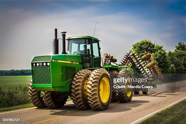 John Deere 8760 farm tractor with a folded farm tractor disc attached driving down a country road in Indiana.