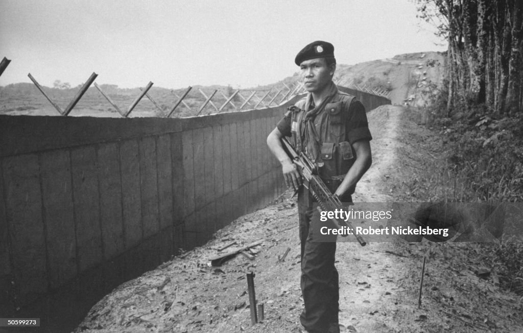 Armed Thai soldier standing guard next t