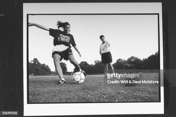 Univ. Of NC soccer coach Anson Dorrance instructing star player, all-American forward Mia Hamm, as she kicks ball during practice on the Univ's...