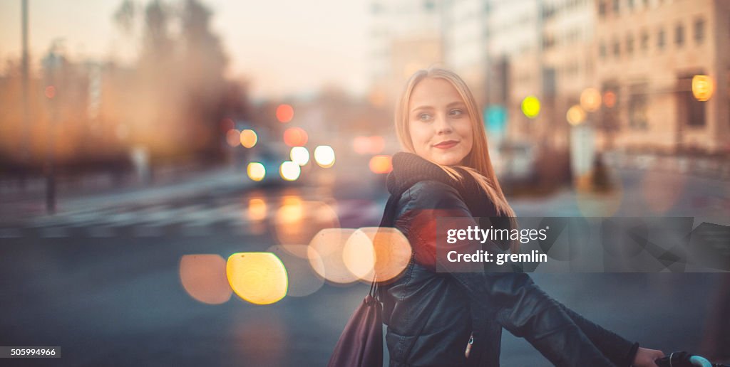 Young woman crossing the street with bicycle