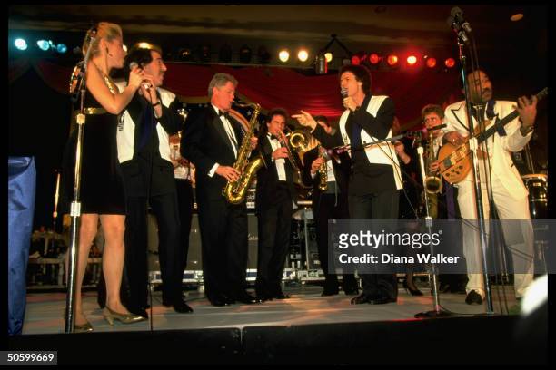 Pres. Bill Clinton playing saxophone, jamming w. Musicians onstage at DC Armory Ball during inaugural wk. Festivities.