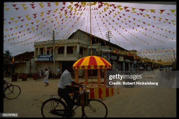 Cyclist passing unmanned traffic booth in street scene festive for wk-long memorial for separatist Tamil LTTE dead in war w. Majority Sinhalese.