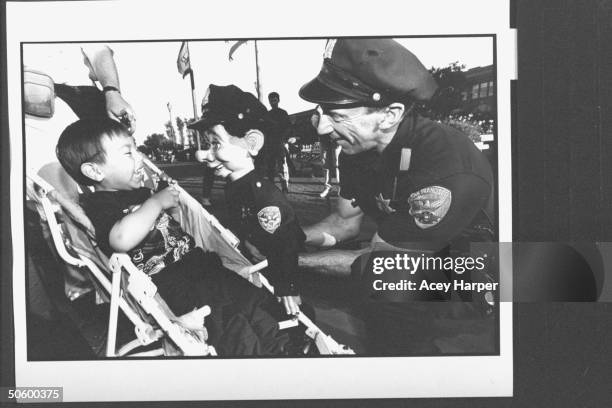 San Francisco police officer Bob Geary w. His partner, uniformed puppet cop Brendan O'Smarty, chatting w. Giggling young boy in a stroller on street...