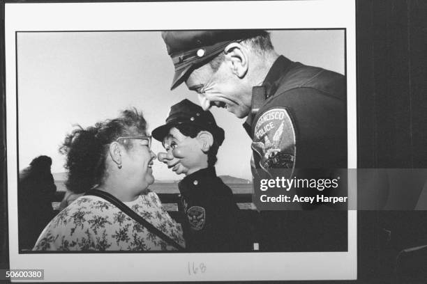 San Francisco police officer Bob Geary w. His partner, uniformed puppet cop Brendan O'Smarty, chatting w. Amused woman on street during their patrol;...