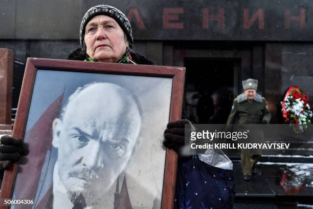 Russian Communist Party supporter carries a portrait of the late Soviet leader Vladimir Lenin as she takes part in a memorial ceremony to mark the...
