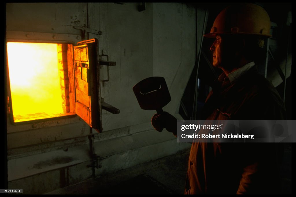 Worker in fiery glow of furnace used at