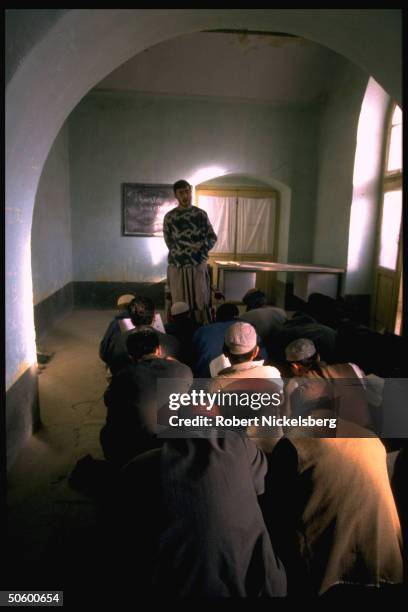 Teacher leading English language class w. All-male old & young student body at facility founded by local teachers.