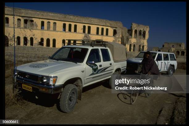 Vehicles by civil war ruins, clearing mines fr. Old war front, making way for water lines in World Health Org. Water supply-restoring project.