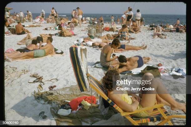 Beach-goers sitting on beach in chairs; Jones Beach.