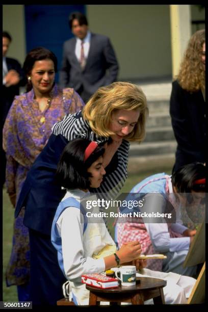 1st Lady Hillary Rodham Clinton watching students paint in art class, at college for girls while on Asian tour w. Daughter Chelsea.