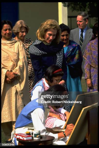 1st Lady Hillary Rodham Clinton watching students paint in art class, at college for girls while on Asian tour w. Daughter Chelsea.