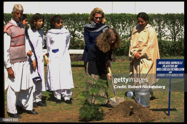 Hillary Rodham Clinton watching daughter Chelsea plant sapling during visit to college for girls, on Asian tour stop in Islamabad, Pakistan.