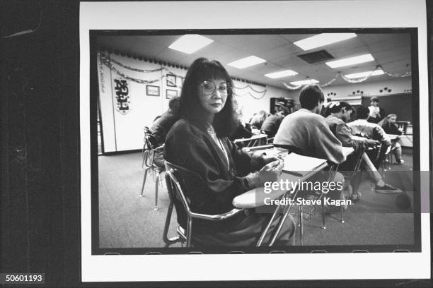 Korean immigrant Yong Duckworth a mom & HS junior, w. Bks. As she sits at desk in classroom w. Other students at Heritage Hills HS; she started back...